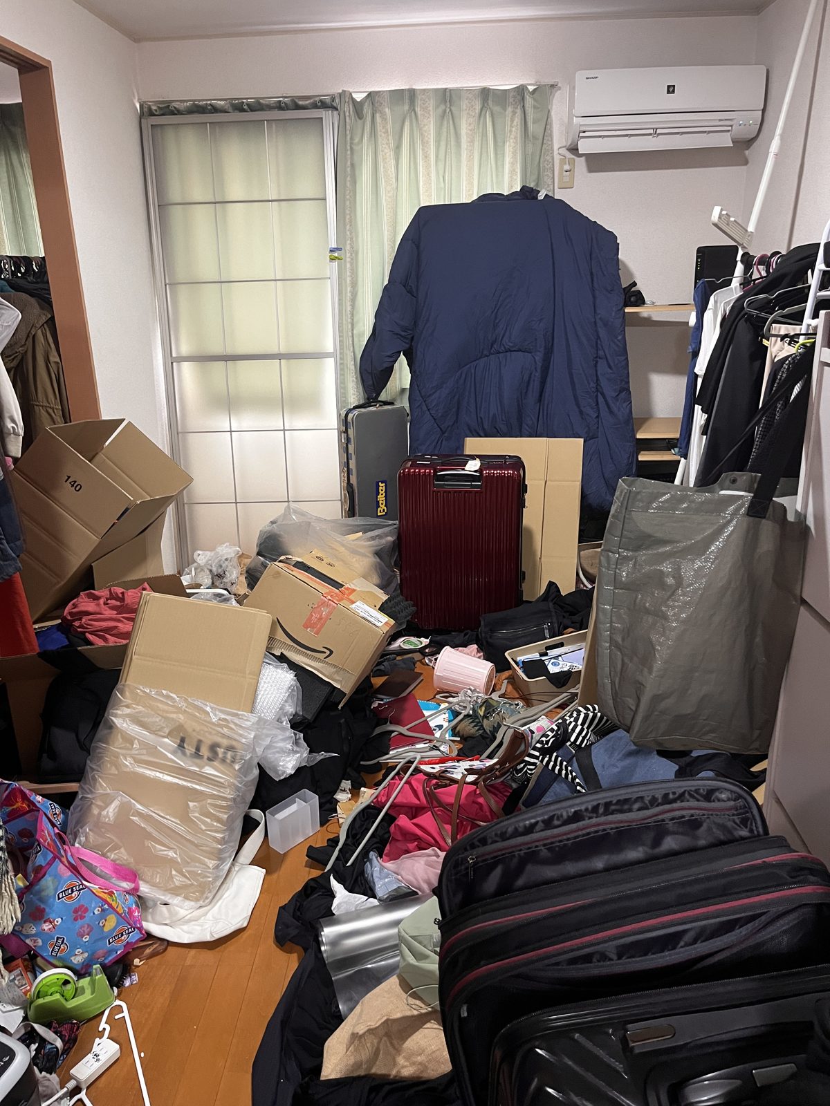 お洋服や荷物で足の踏み場がなくなったお部屋（お片付け前）